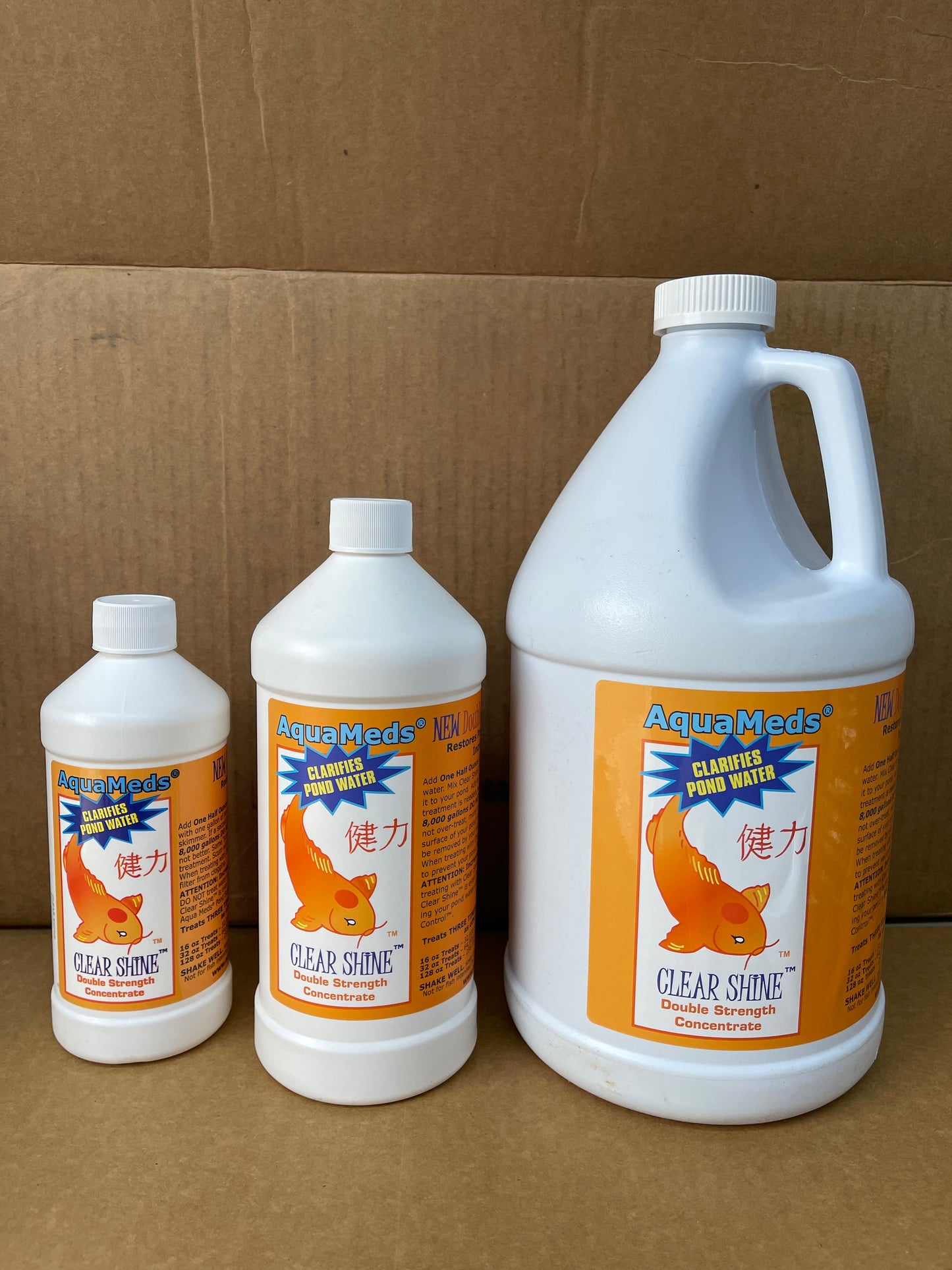 Three sizes of Aqua Meds Clear Shine pond clarifier, white bottles with orange goldfish labels